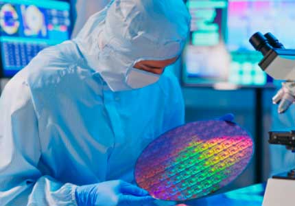 Man in laboratory inspecting semiconductor wafer